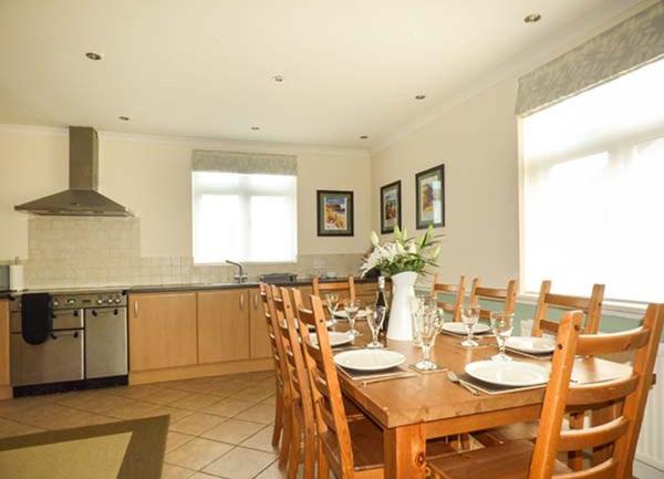 A kitchen diner with fitted units and range cooker and a dining table seating 8.