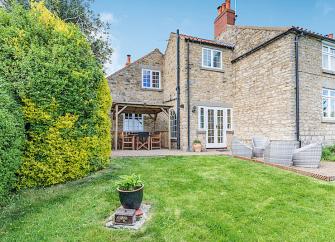 A stoine-built cottage overlooks a large lawn.