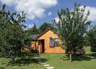 Gable end of a wooden eco-lodge in an orchard setting.