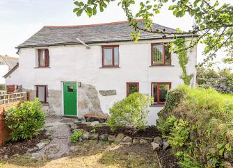 A 2-storey Cornish cottage overlook a tree-lined garden.