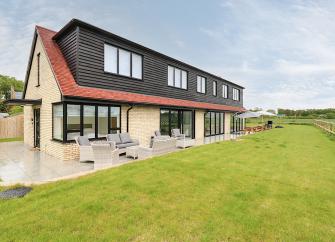 A contemporary 2-storey brick house surrounded by open fields.