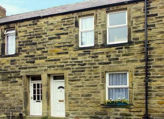 Stone-built terraced cottage with a flower-filled window basket.