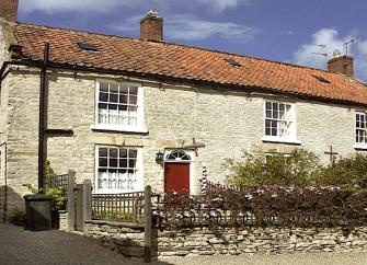 A semi-detached cottage overlooks a stone-walled front garden.