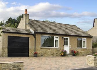 A modern holiday bungalow with a large block-paved parking area