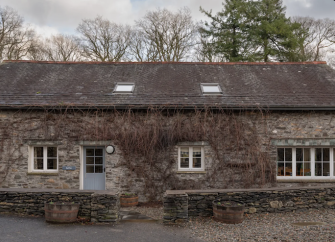 A stone-built, vine-clad barn conversion behind a low stone wall