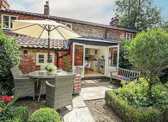 Floor to ceiling French windows in a brick and coblestone cottage overlook a formal garden.