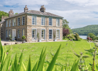 Exterior of a country house in the Lake District with a lake in the background.