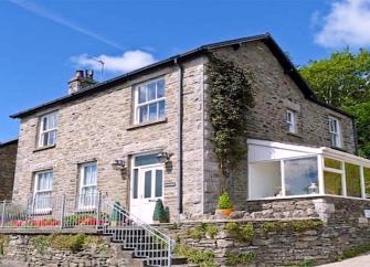 A large Cumbrian with spacious sunroom with a raised, flower-filled terrace.