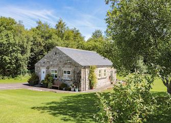 A single storey Northumberland barn conversion surrounded by a large, tree-fringed lawn