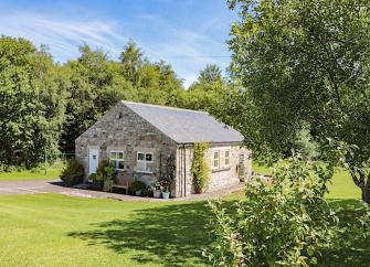 A single storey Northumberland barn conversion surrounded by a large, tree-fringed lawn