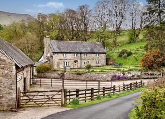 A pair of slate-roofed stone cottages in Herefordshire with large gardens overlook a counry lane.