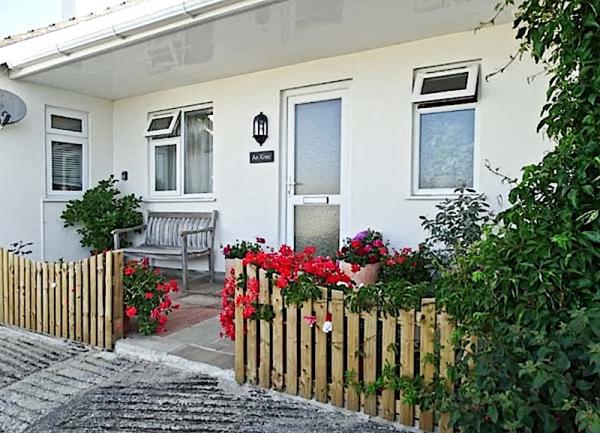 Exterior of a single-storey coach house convrsion with a small, flower-filed front garden.