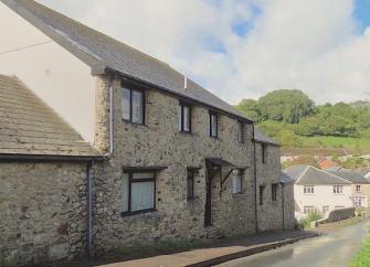 Exterior of a double-fronted, stone-built cottage overlooking a quiet village street in East Devon. 