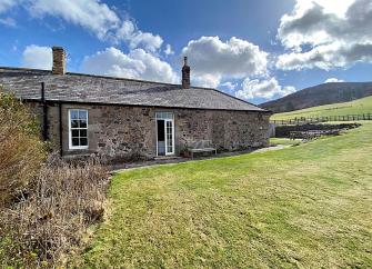 Large lawns surround a ground-floor barn conversion in remote, open Northumberland countryside