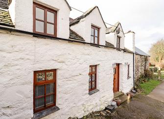 A white-washed stone cottage overlooks a country lane in North Wales