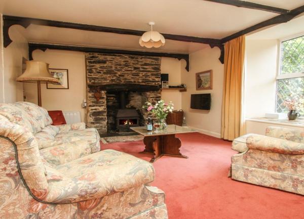 A lounge with a window seat, armchairs, coffee table, and inglenook fireplace.