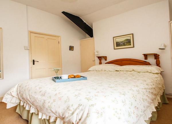 Double bedroom with a bed, bedside wall-lights, fitted wardrobe and large mirror.