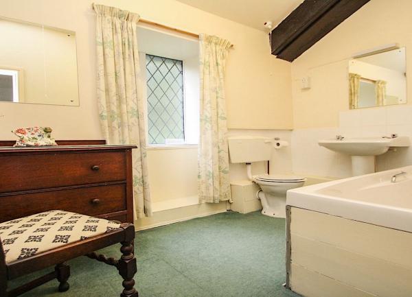Bathroom with a bath, washbasin and WC, chest-of-drawers and a chair.