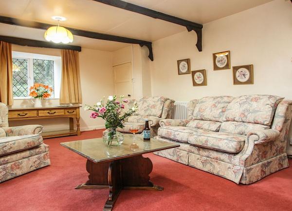 A carpeted lounge with a sofa, two armchairs, a coffee table and standard lamp.