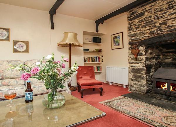 A carpeted lounge with a double window, sofa, armchairs and side-tables.