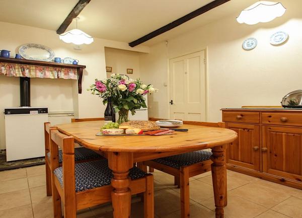 The dining area with wooden table, chairs, a sideboard and a boiler in the old fireplace.
