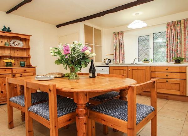 A kitchen-diner with dining table, wooden chairs, a dresser and fitted units.