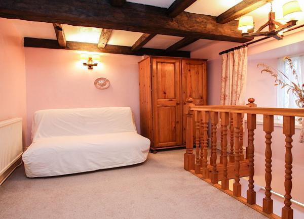 Top floor bedroom with double bed, stout oak beams, a wardrobe and bannisters around stairs down.