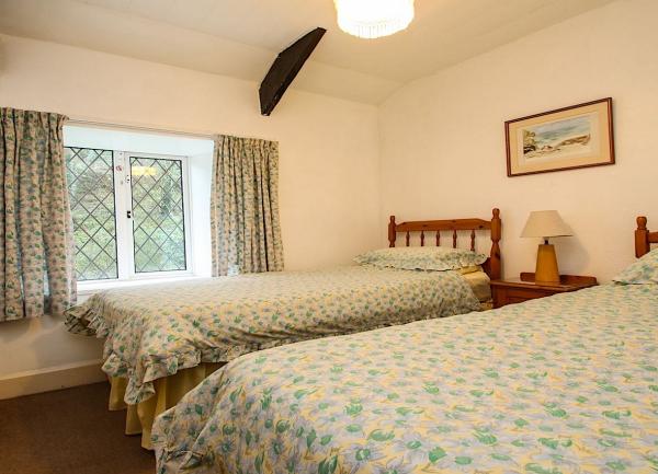 Twin bed room with beds, fitted wardrobe and double window with  latticed glass.