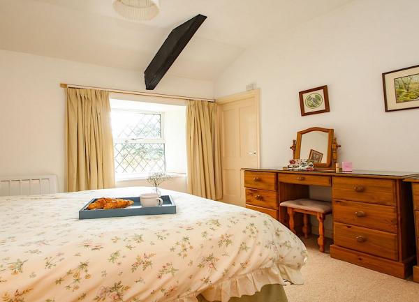 Double bedroom with a bed, large dressing table and a chest-of-drawers.