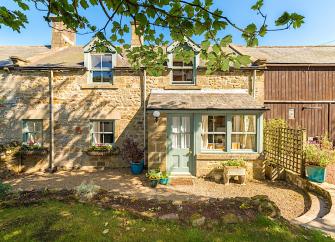 Exterior and front garden of a 2-storey stone-built Northumberland holidy cottage.