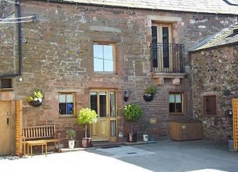 A stone Penrith holiday home with a 1st floor Juliet Balcony overlook a paved courtyard.