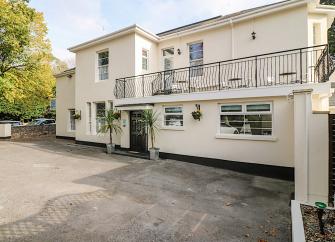 Exterior of a large Victorian house in Torquay with a long balcony overlooks a courtyard.