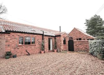Exterior of a brick-built holiday bungalow in Fakenham with spacious off-road parking.