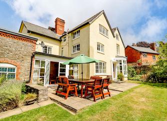 3 storey exterior of a large modern Shropshire holiday home with outdoor dining facilities and a large laen.