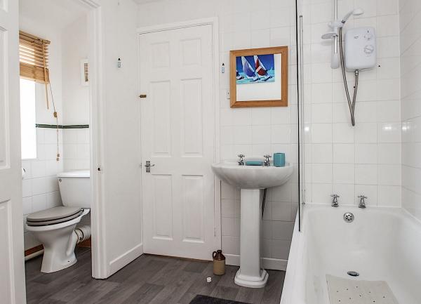 A bnathroom with a bath having a shower over, basis and WC.