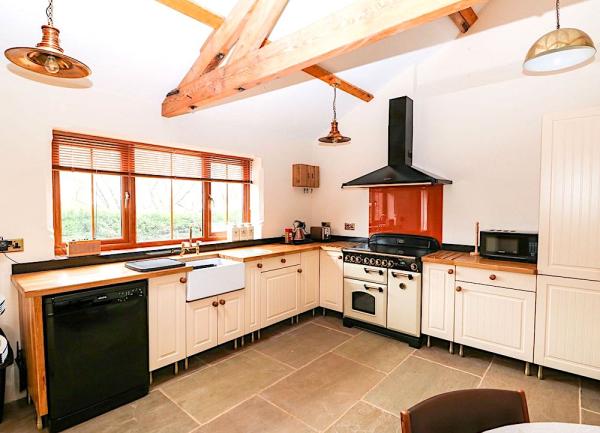 A fitted kitchen of floor cupboards with integrated units including a dishwasher, range cooker and microwave.