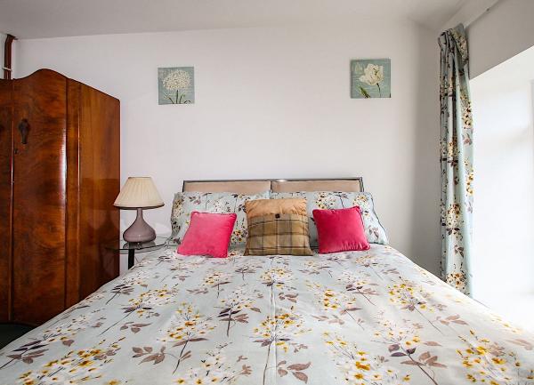 A double bed with cushions and a bedside table light.