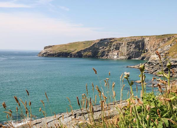 High, rugged cliffs curve around a bay and a calm sea.