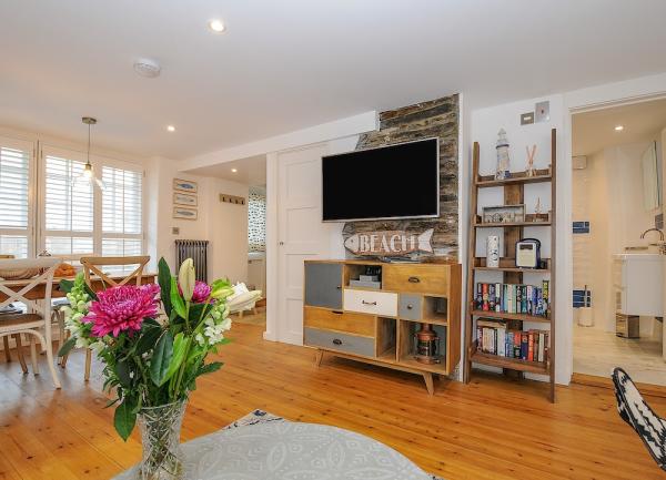 A wood-floored lounge with a TV, sideboard, book case and coffee table.
