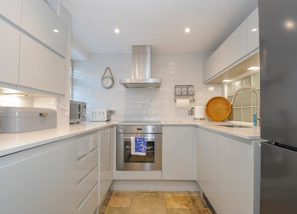 A modern fitted kitchen with a U-shape of. units, an oven and other appliances on worktops.