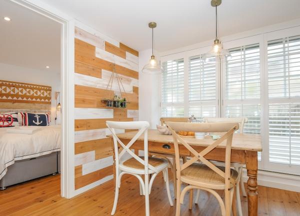 A dining area with wooden table and chairs and two overhead light shades.