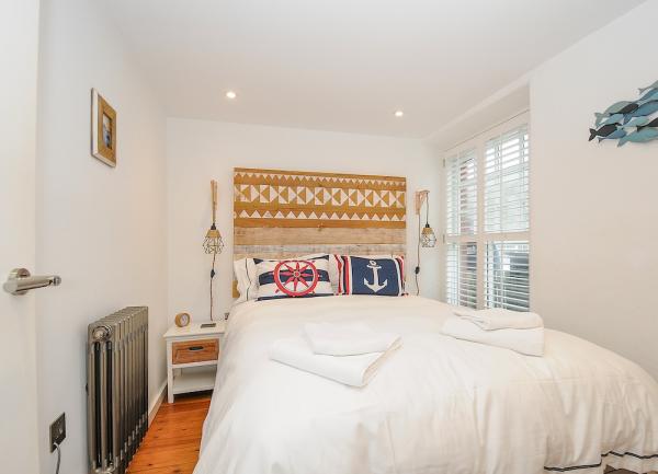 A double bedroom with  a large bed, wall lights, bedside cabinets and a radiator.