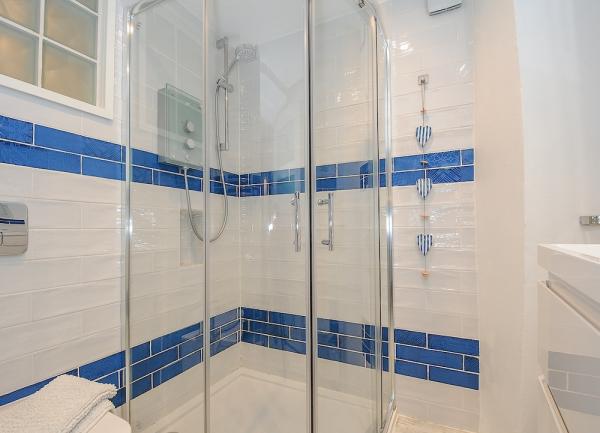 A gleaming tiled bathroom with a large 'rain-drench' shower and wash basin.