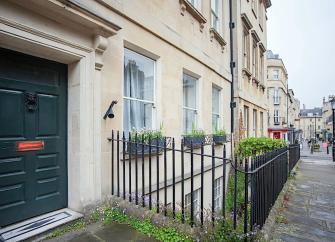 A 4-storey, classic Bath-stone terraced house overlooking a street.