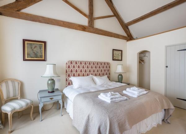 Double bedroom with bed, fitted wardrobe, armchair and bedside tables with lights.