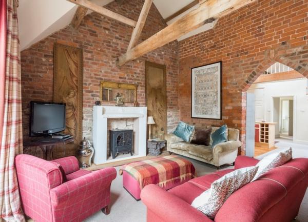 Lounge  with exposed brick walls,  wood burner, two sofas, an armchair and TV
