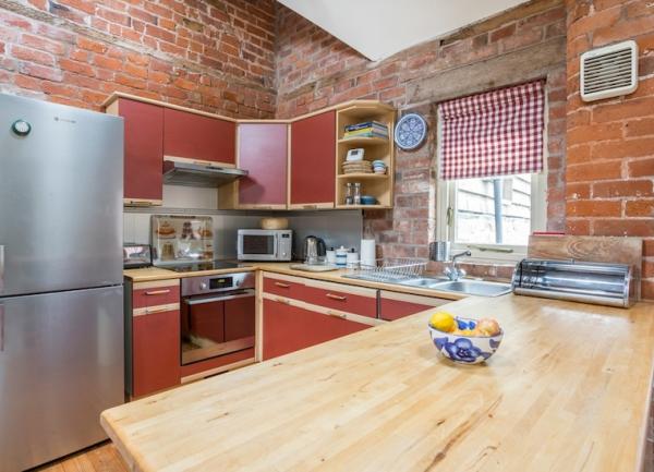 Kitchen with pine worktops, cooker, full-height fridge freezer and microwave.