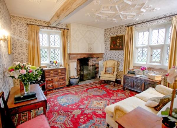 Dual aspect living room with leaded windows, sideboards and a sofa.
