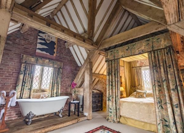 Dual aspect oak beamed bedroom with 4-poster bed and a bath.