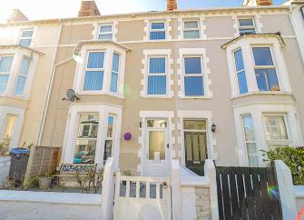 Exterior of a 3-storey Victorian townhouse in Llandudno with large bay windows.